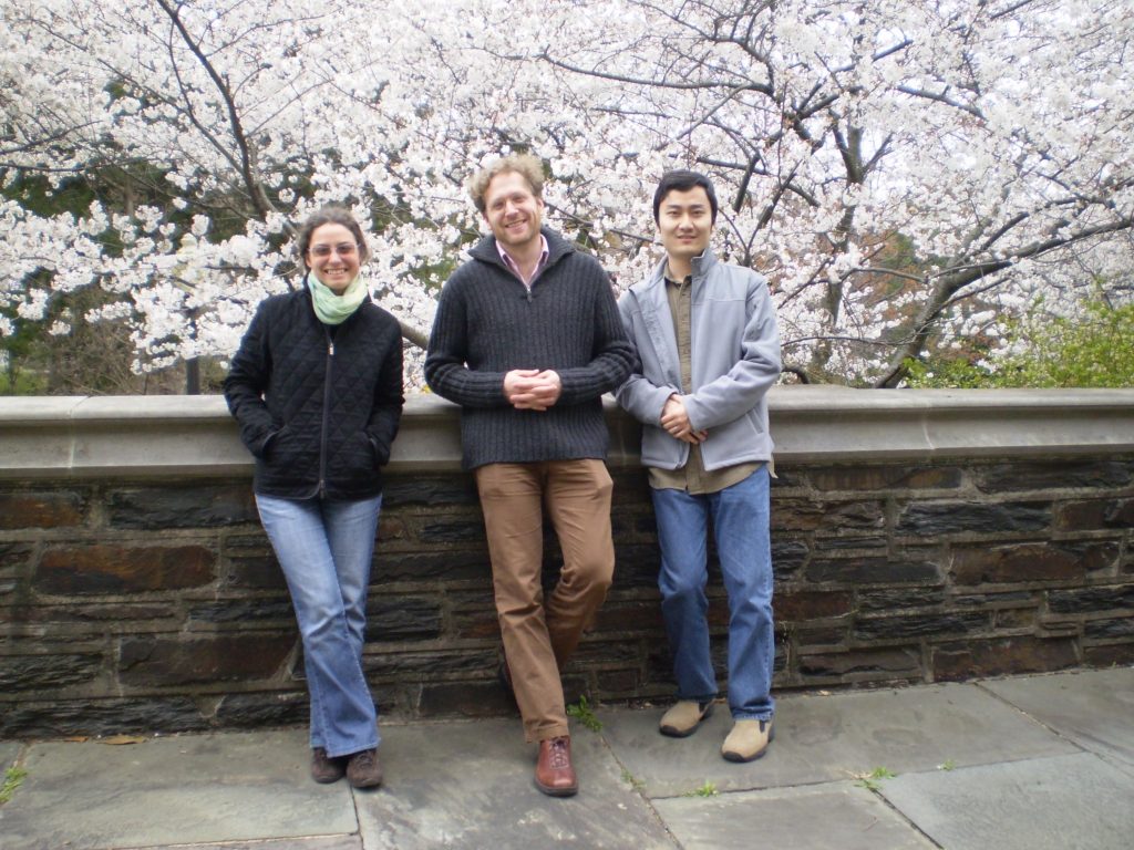 3 people pose in front of blooming tree