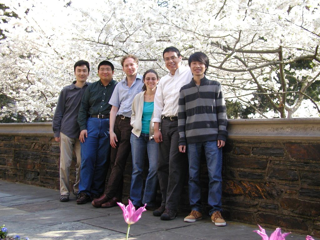 6 people pose in front of a blooming tree