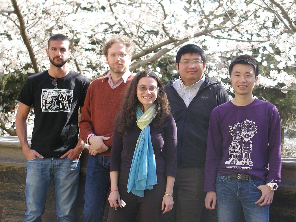 5 people pose in front of a blooming tree