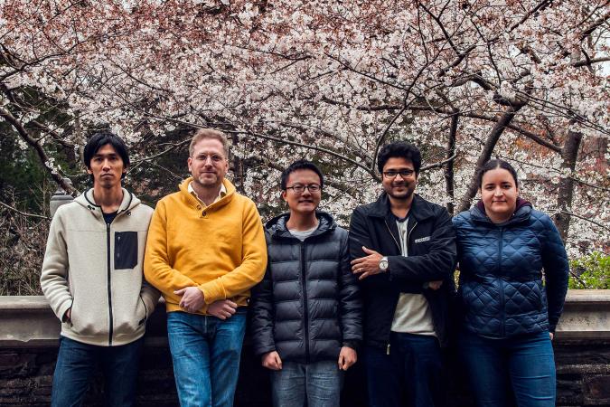 5 people stand in front of a blooming tree